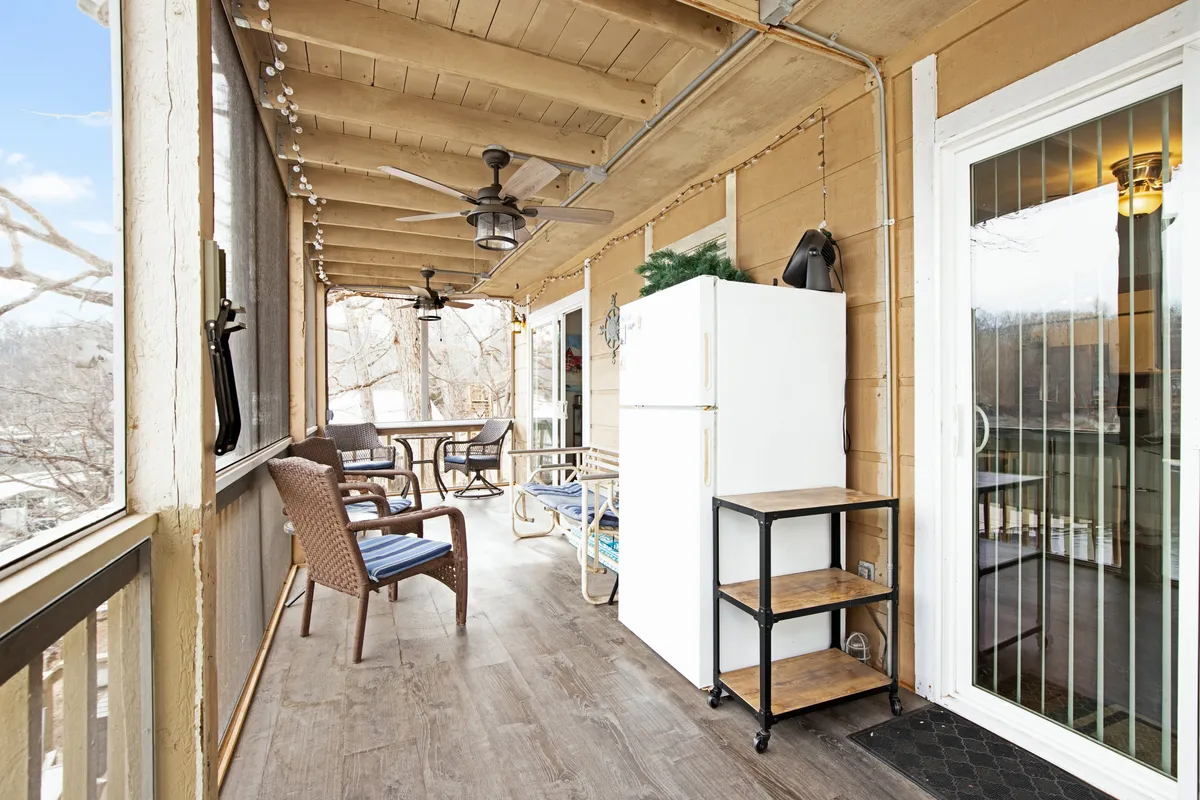 A screened-in patio with outdoor furniture, an extra refrigerator, and ceiling fans, accessed by a sliding glass door—ideal for relaxed gatherings and dining outdoors regardless of the weather.