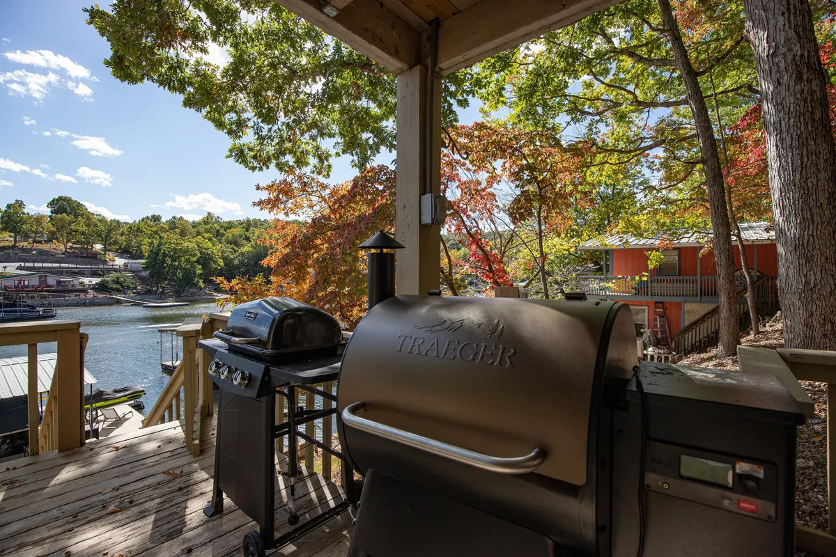 An exterior shot featuring a grill with lake views framed by vibrant autumn foliage, suggesting outdoor cooking and alfresco dining experiences.