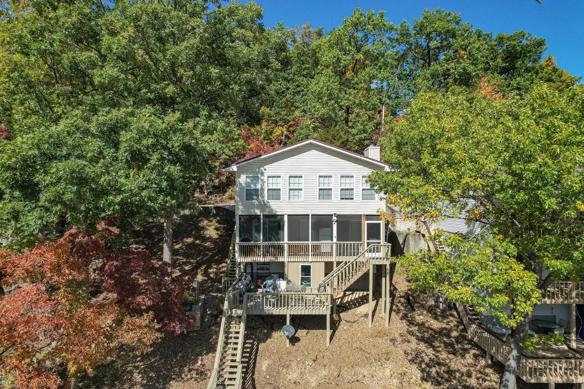 A tranquil exterior view of the house featuring a spacious deck surrounded by trees, perfect for outdoor barbecues, family gatherings, and soaking in sunset views over the lake.