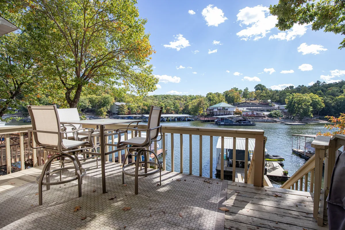 An inviting outdoor seating area with comfortable chairs arranged to take in the sweeping lake views. The patio is surrounded by lush trees and offers a relaxing space perfect for enjoying meals, morning coffee, or evening drinks with friends.