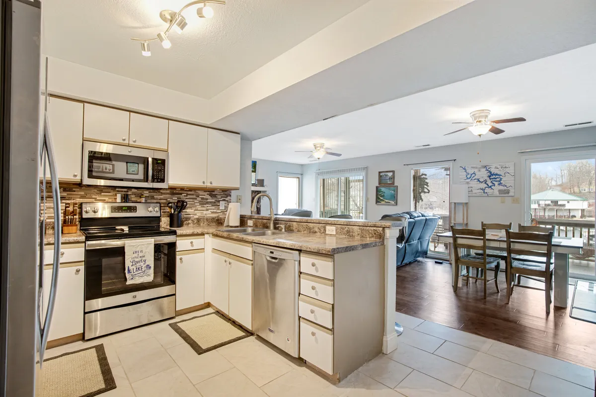 A welcoming kitchen with generous countertop space and stainless steel appliances, seamlessly opening up to a dining area with views outside. The kitchen features a modern, functional layout ideal for group cooking and entertaining.