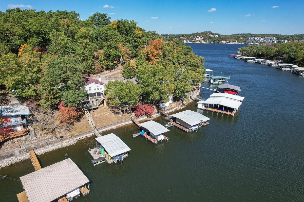 This exterior image showcases wooden docks extending into calm water, flanked by boathouses and lush greenery. The serene scene suggests easy access to boating and fishing, and the natural setting highlights the peaceful lakeside environment.
